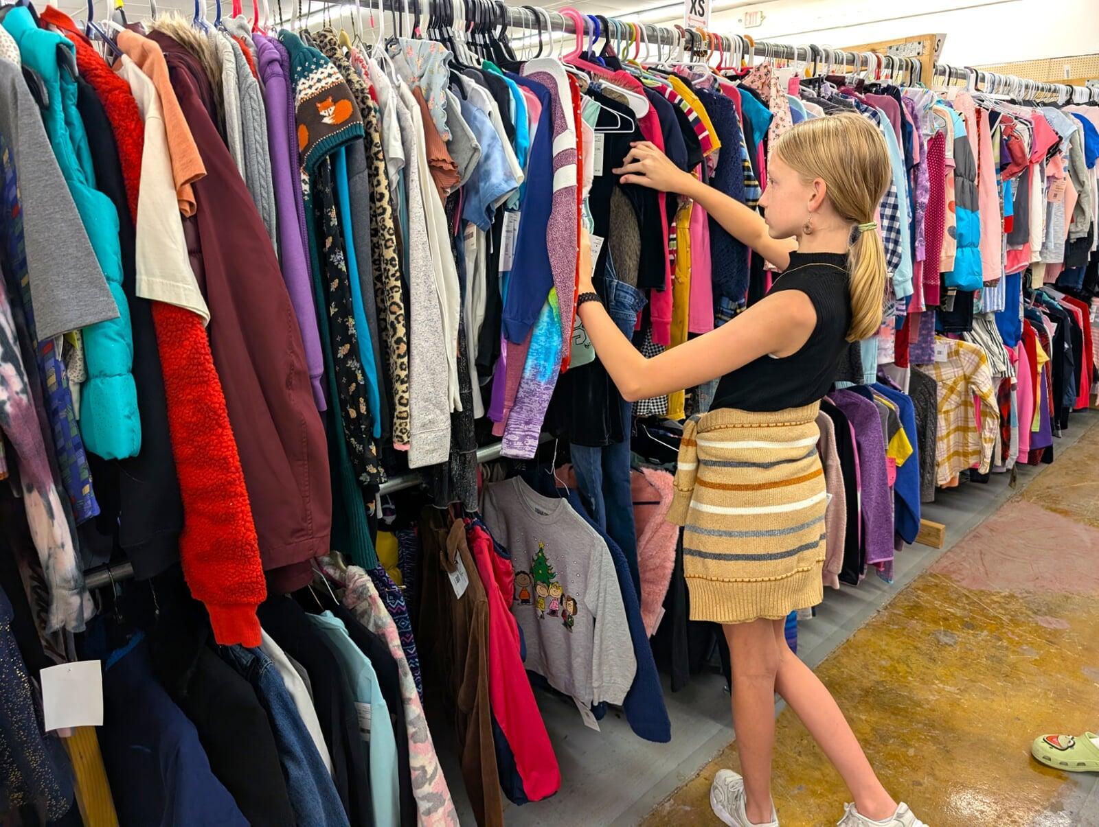 A 12 year old girl looks at racks of clothing