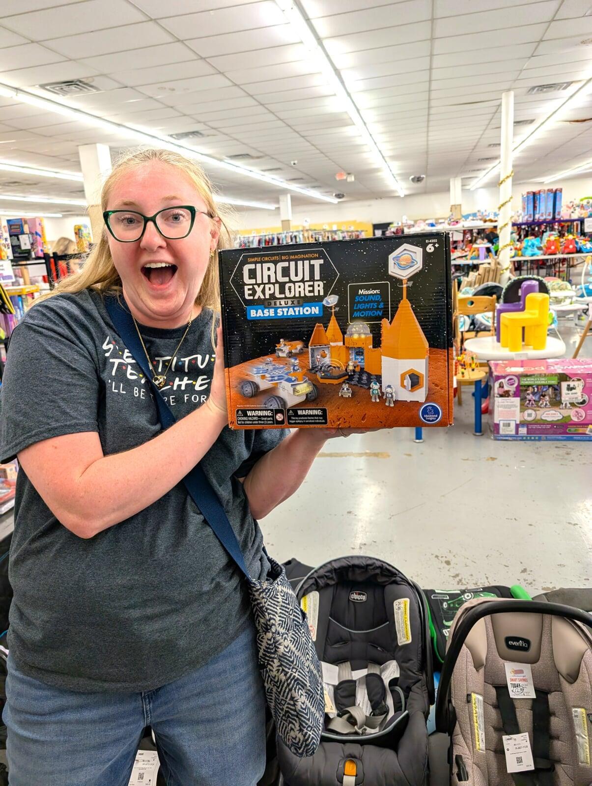 A woman holds a box of science experiments and appears very excited